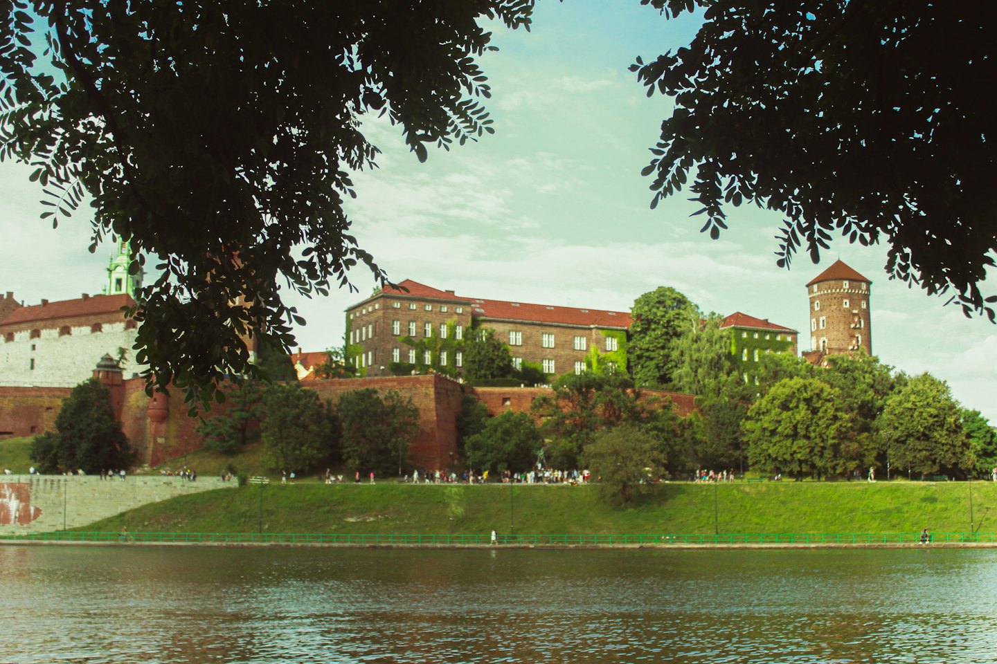 Complexe de château historique avec une haute tour de pierre surplombant une rivière.