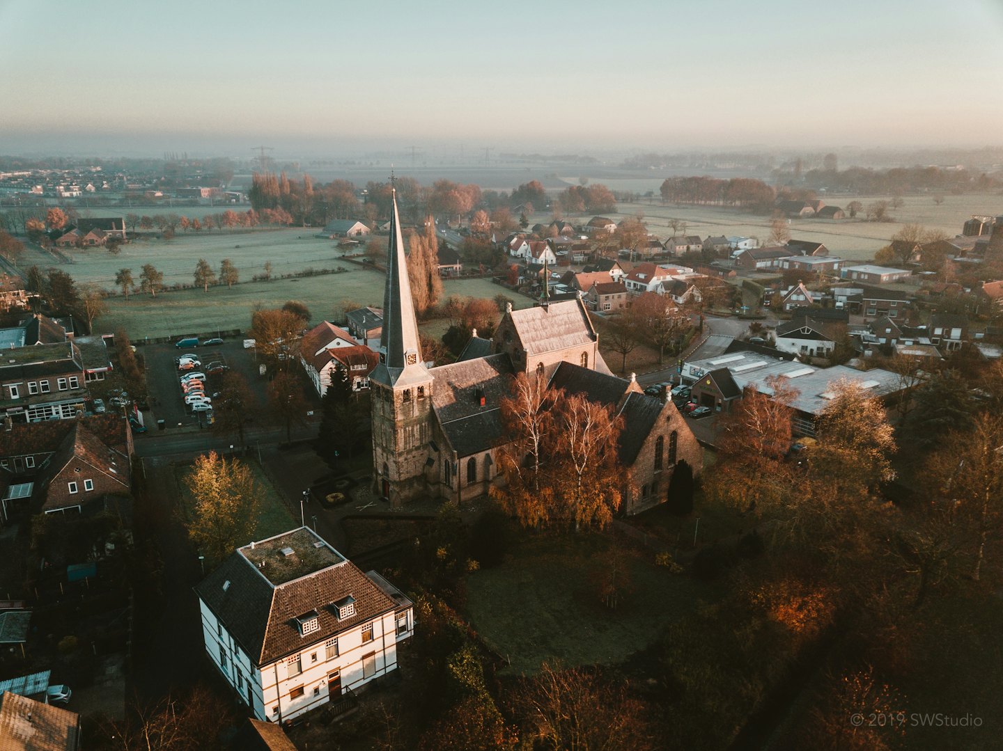 Vue aérienne d'une église de village entourée d'arbres d'automne.